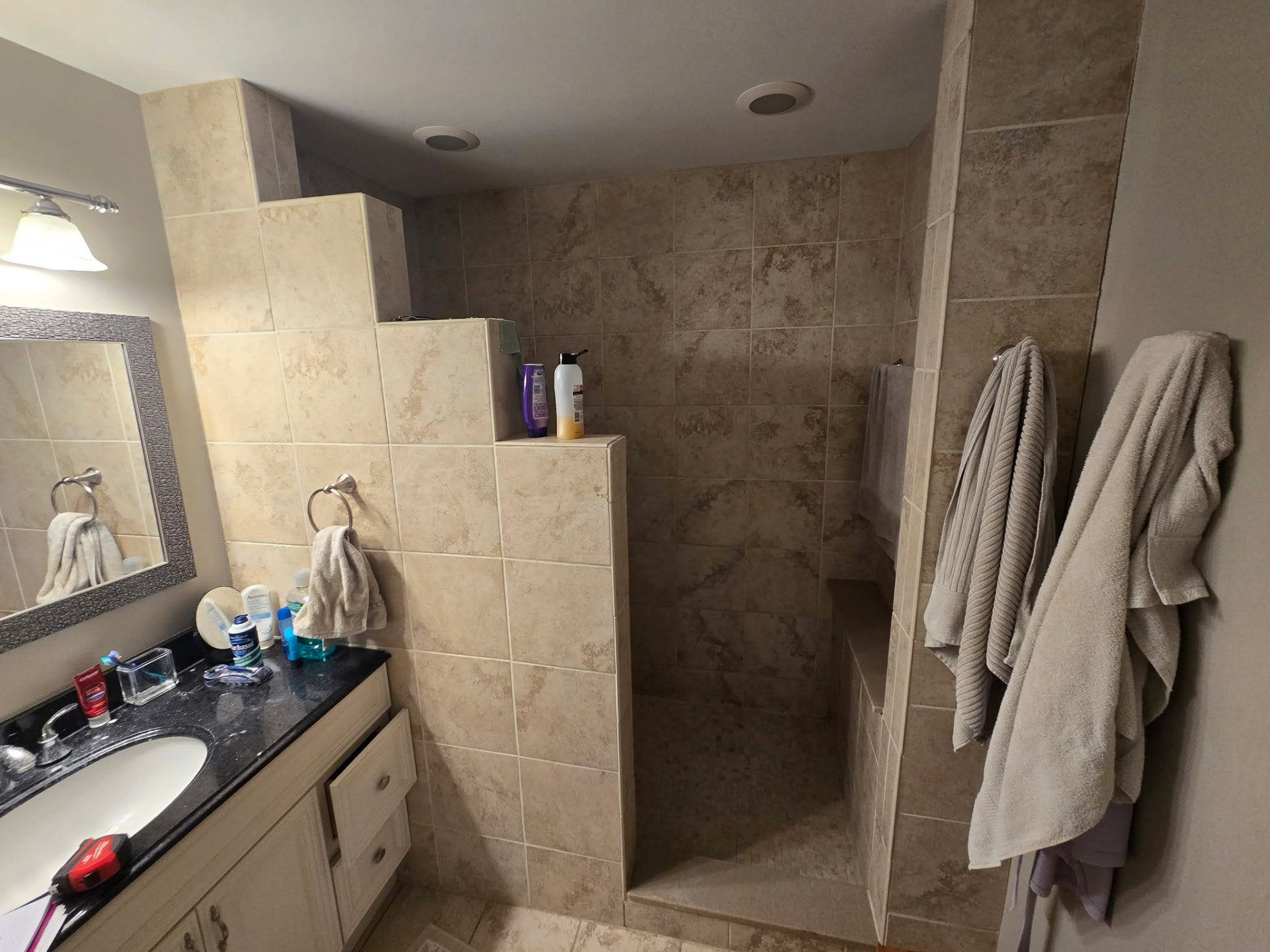 Before: dated beige tile walk-in shower and dark granite vanity in the Lockport bathroom