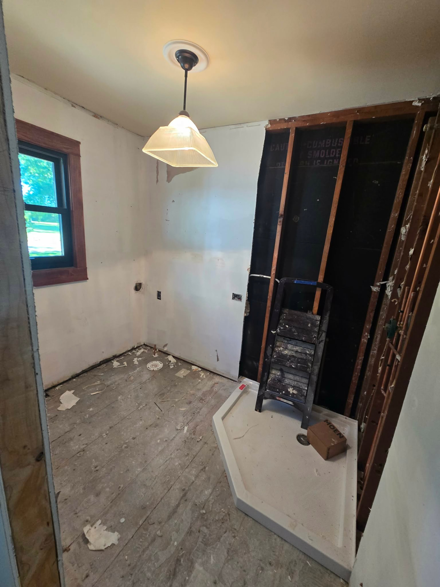 Before: the old laundry room stripped to the studs with the subfloor exposed and a new neo-angle shower base set in place