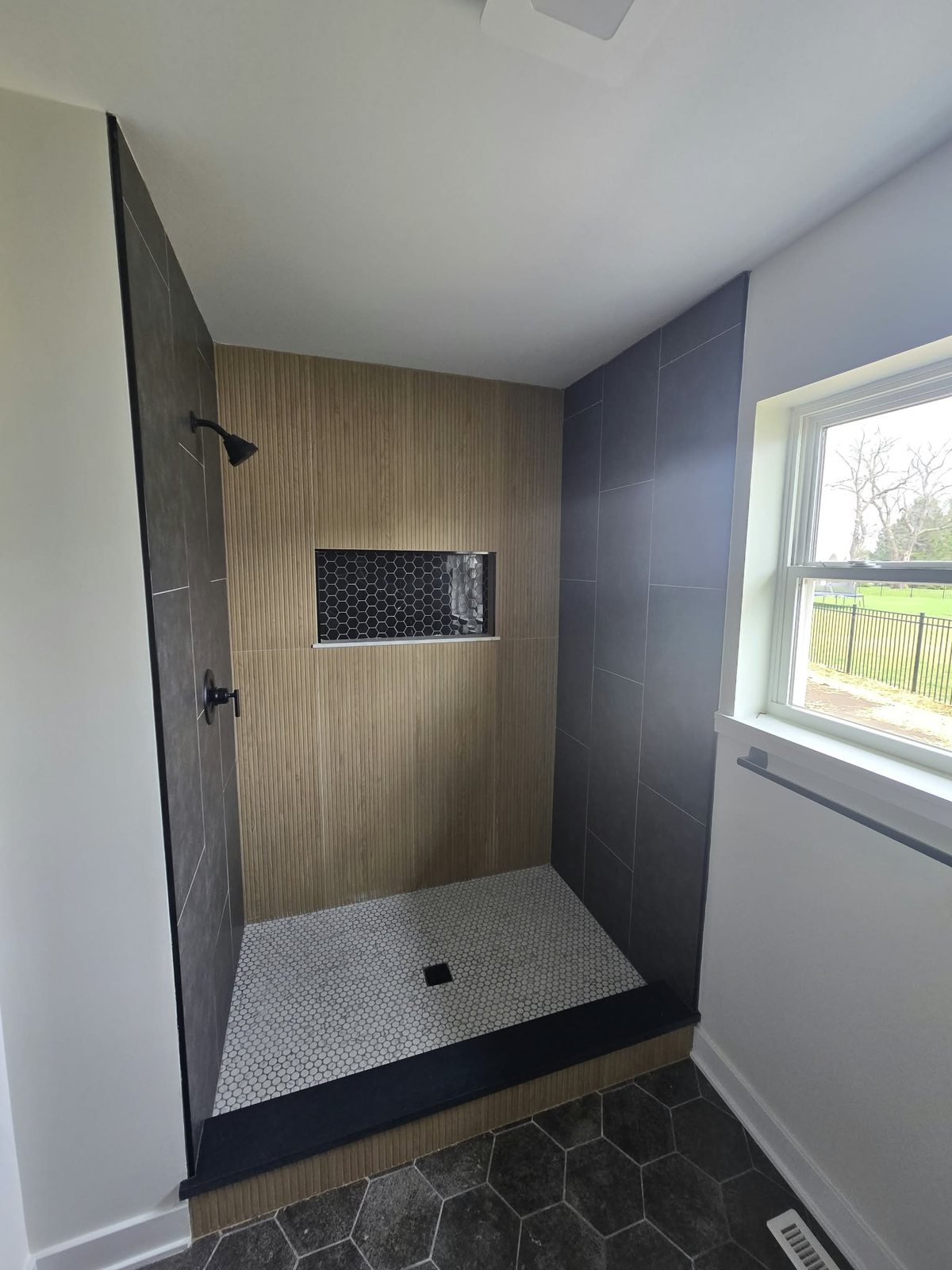 Finished 36 by 48 inch walk-in shower with wood-look and charcoal tile and a recessed niche