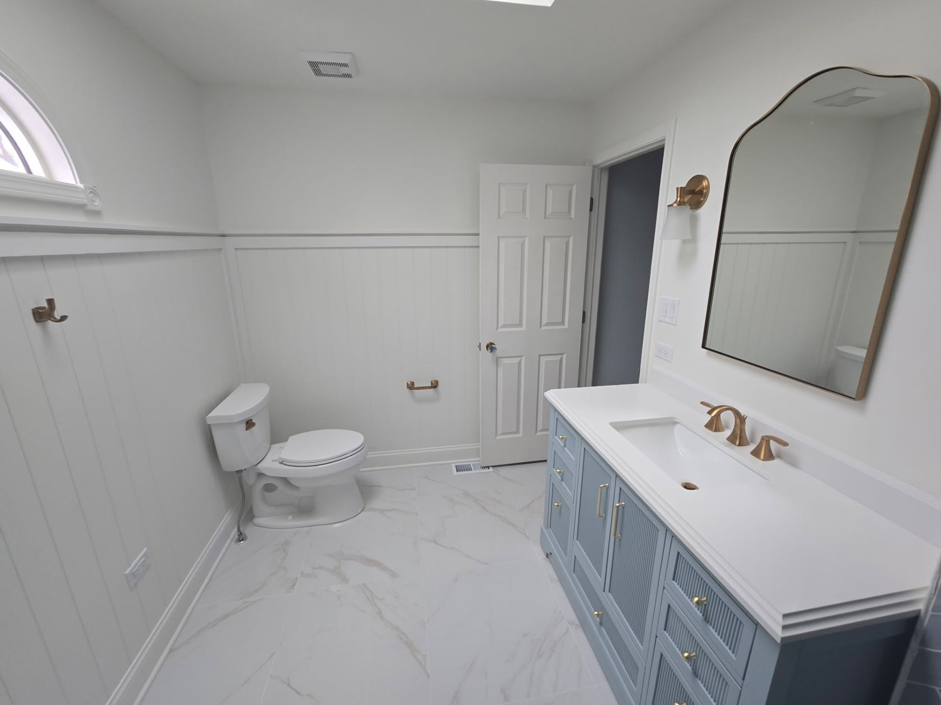 Wide view of the finished Lockport bathroom with vanity, mirror, and paneled walls
