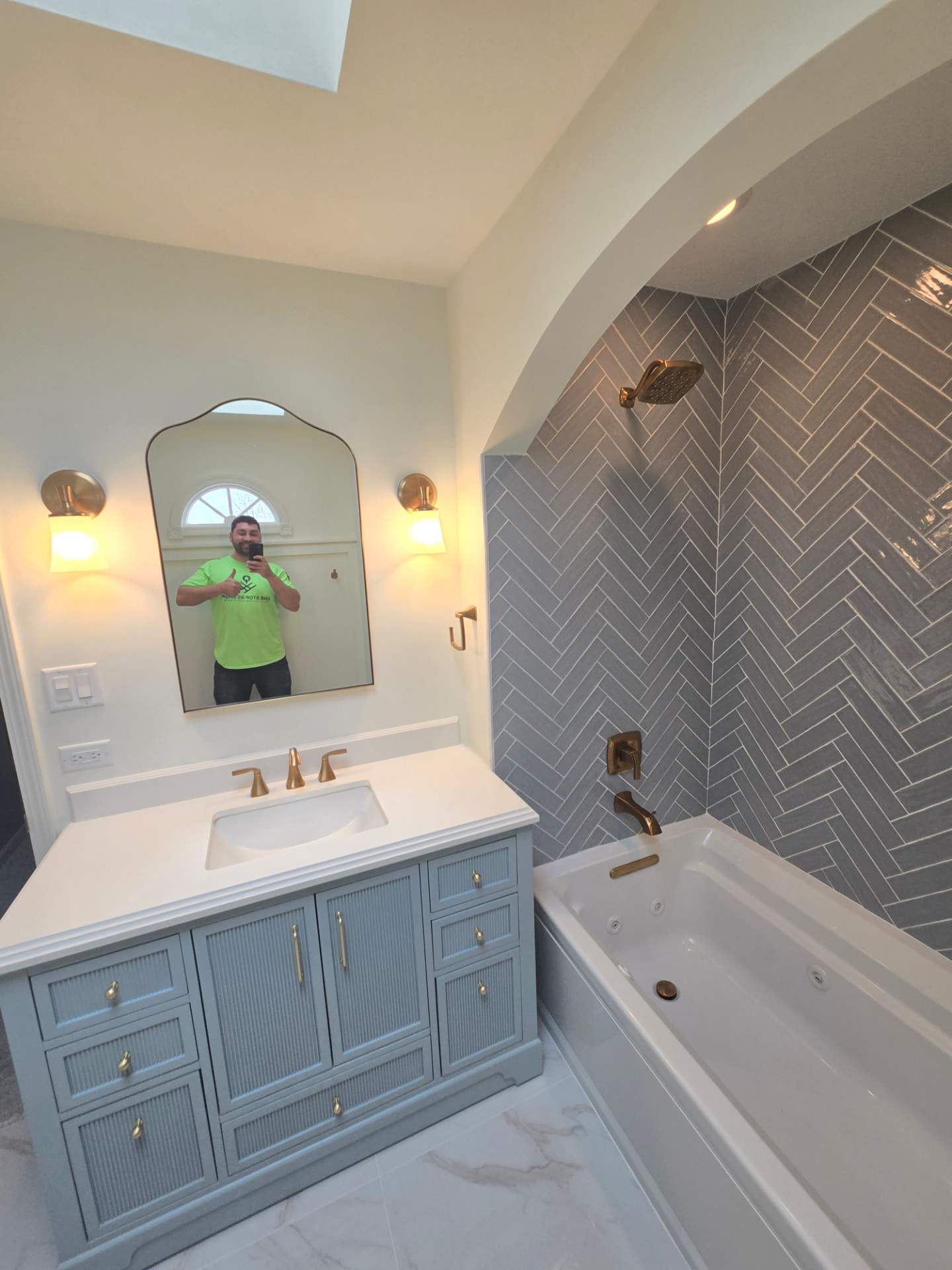 One Stop RE Shop contractor in green branded shirt taking a mirror selfie inside the completed Lockport bathroom remodel