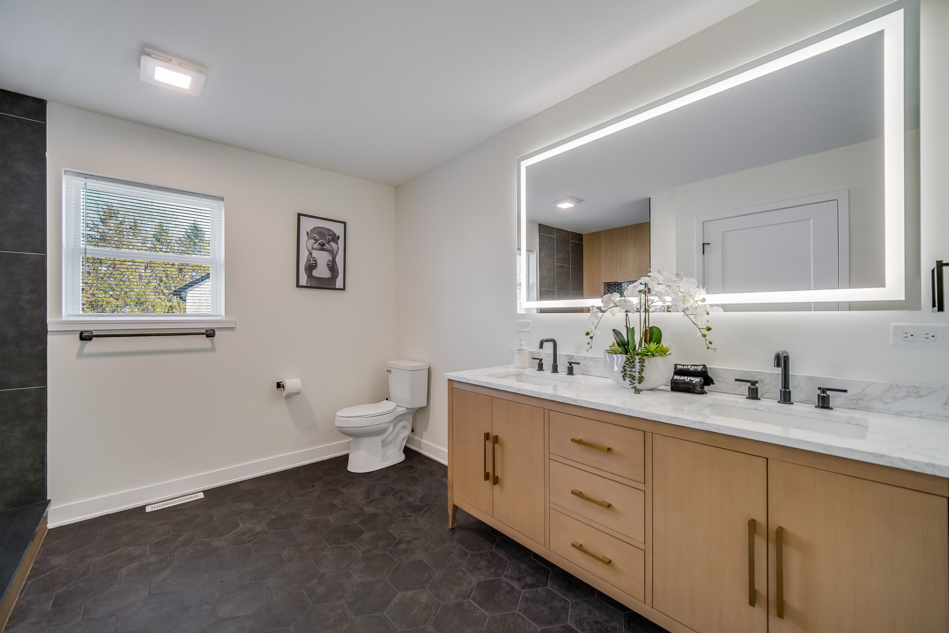 Primary bathroom with double vanity and backlit mirror