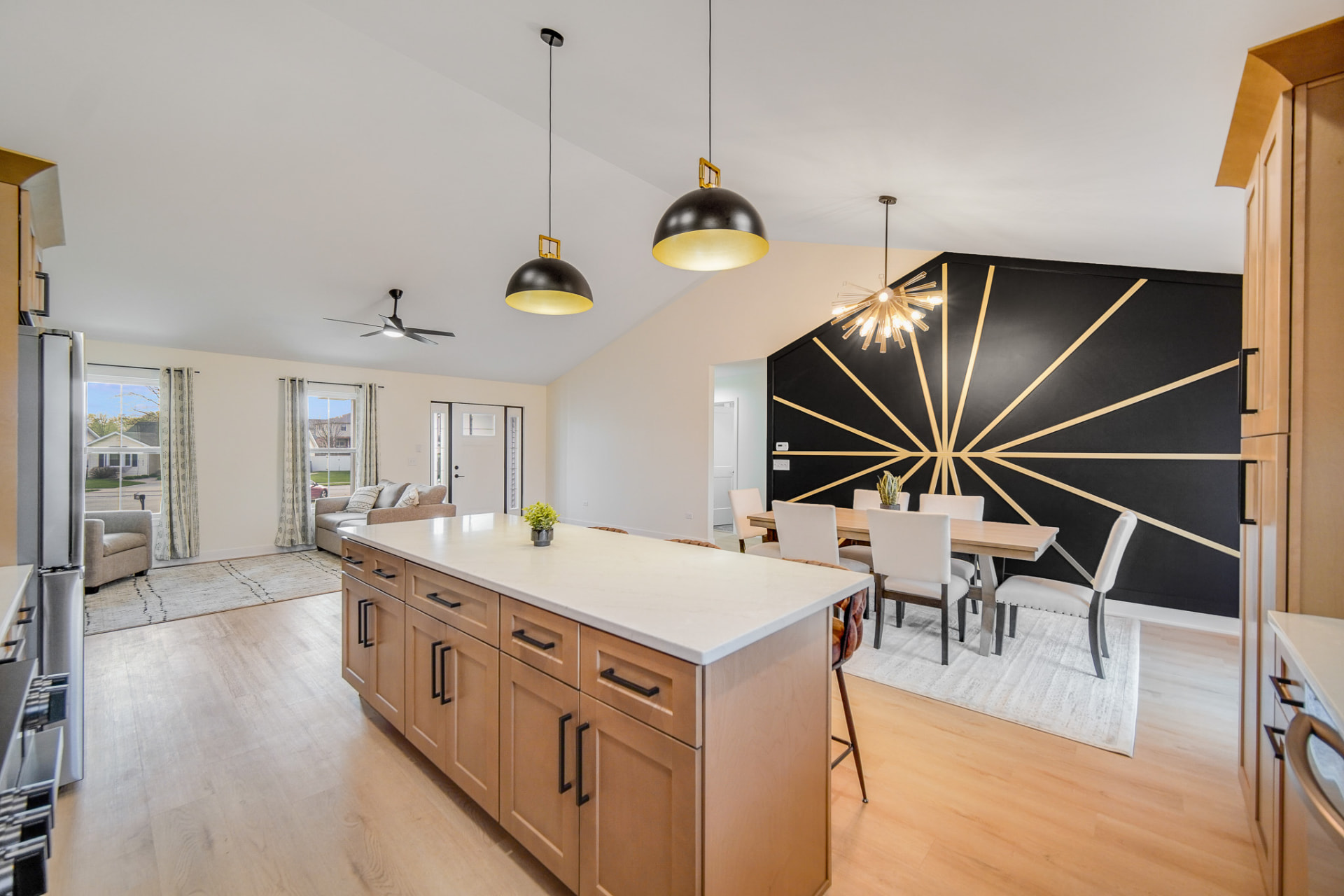 Open-concept living and dining space with black and gold sunburst accent wall