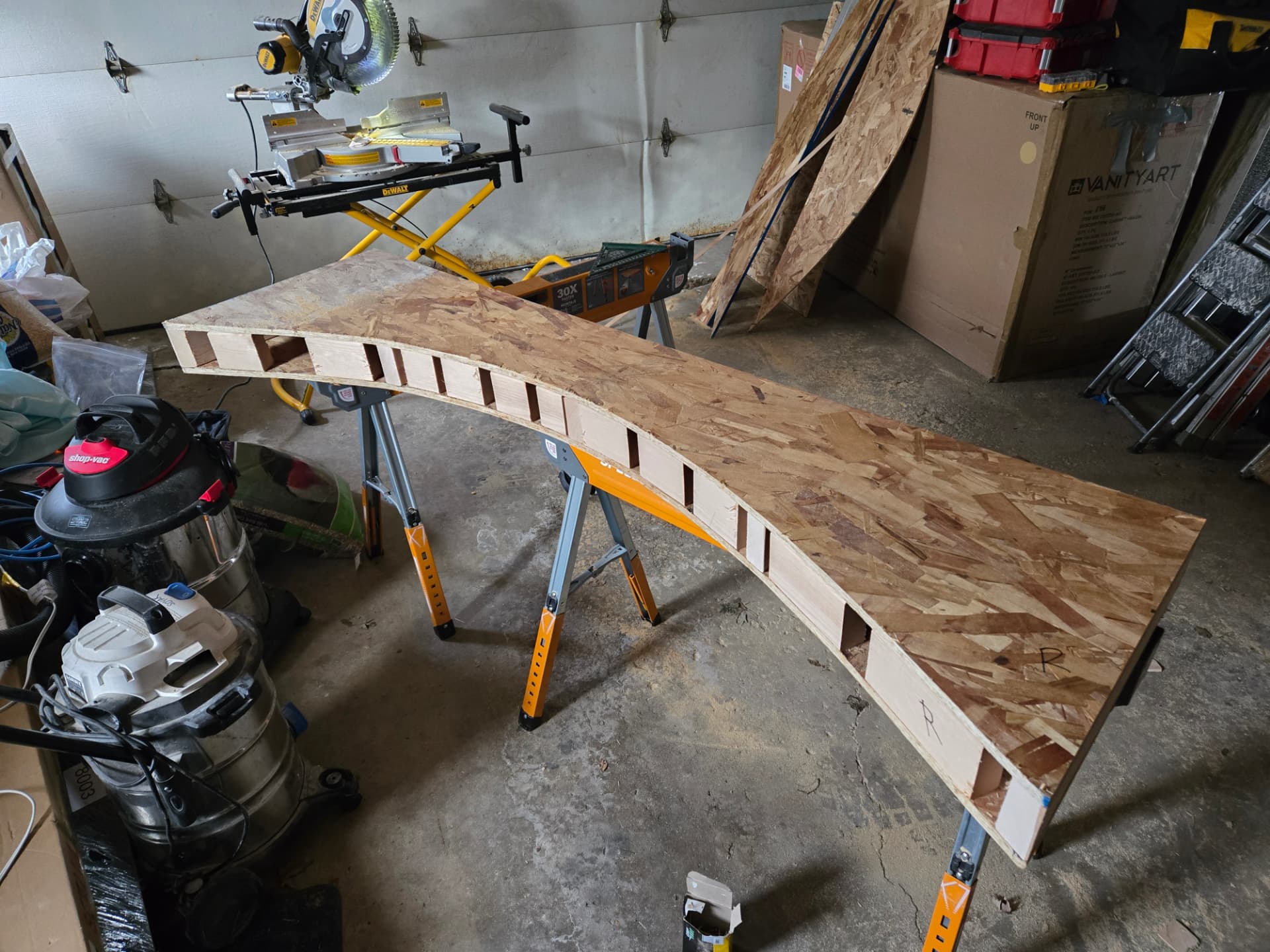Custom wood bathroom arch being fabricated for Lockport remodel from OSB and wood blocking on sawhorses in a workshop