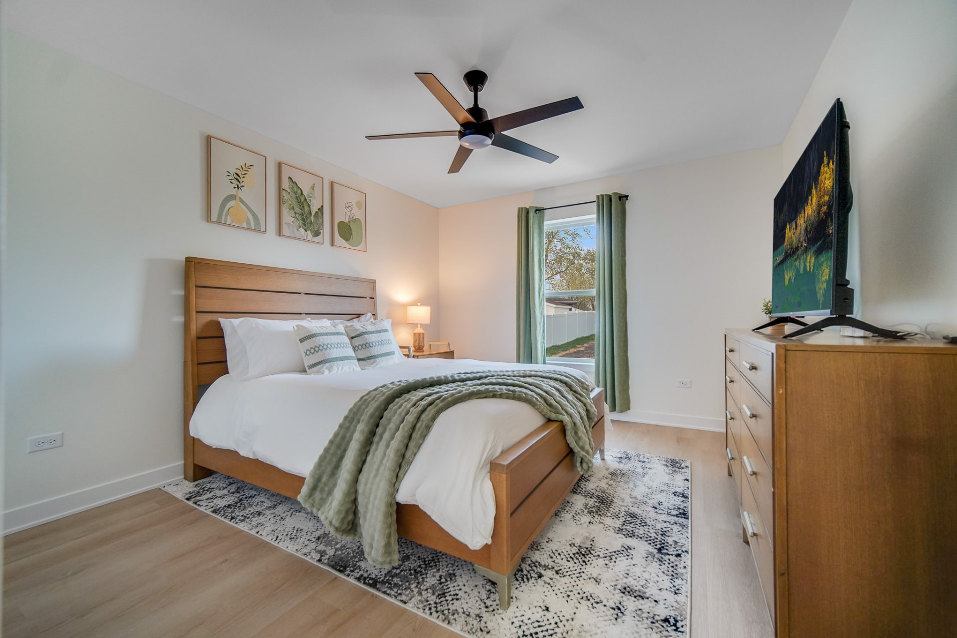 Guest bedroom with wood bed frame and soft green accents