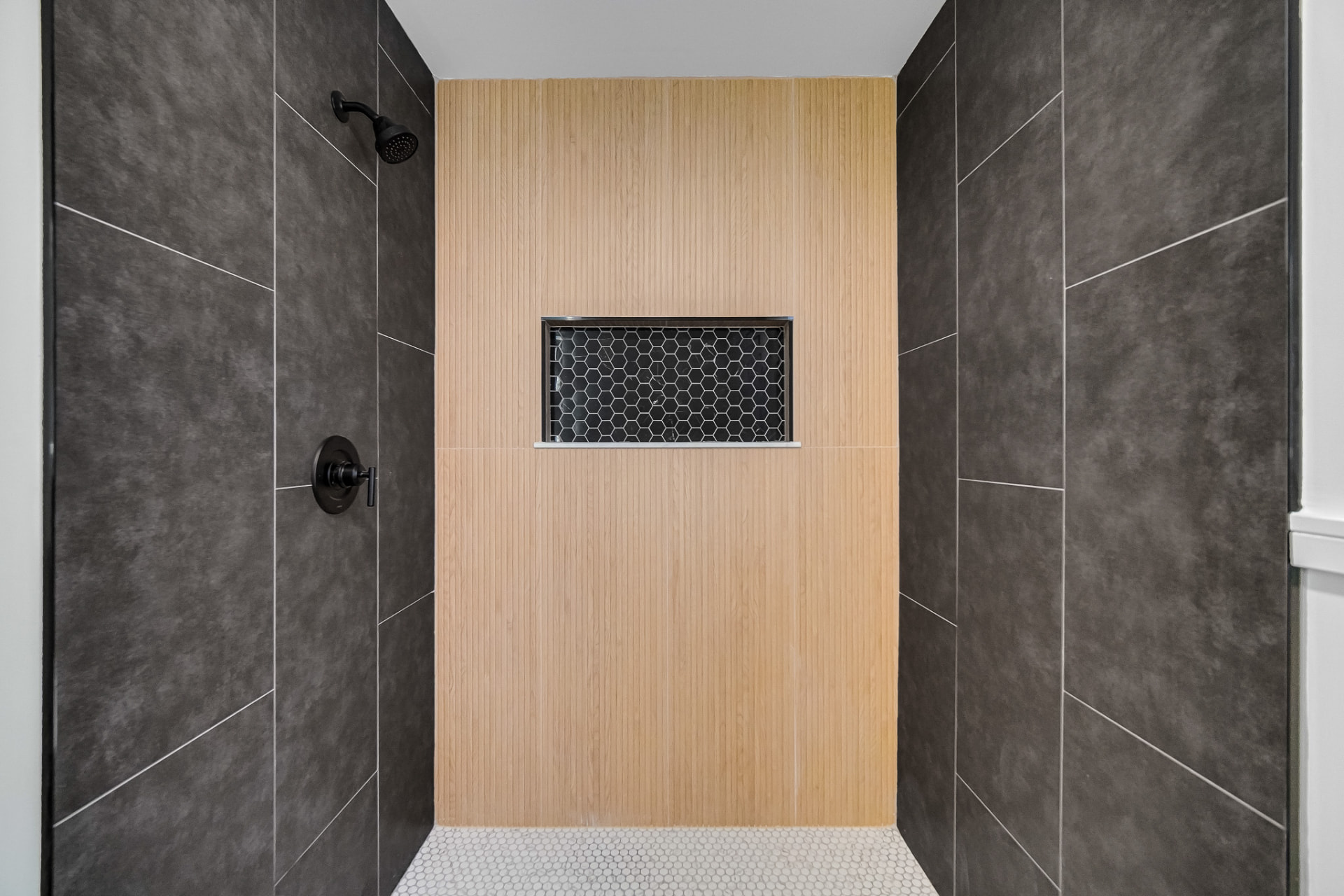 Tiled walk-in shower with fluted oak accent wall