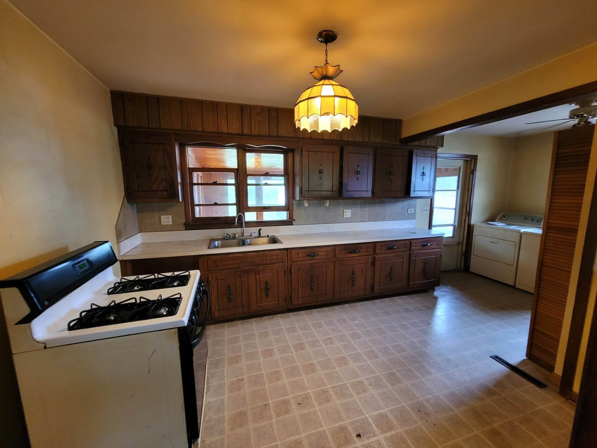 Before: dark 1970s wood cabinets, tile backsplash, and vinyl floor in the Mokena kitchen