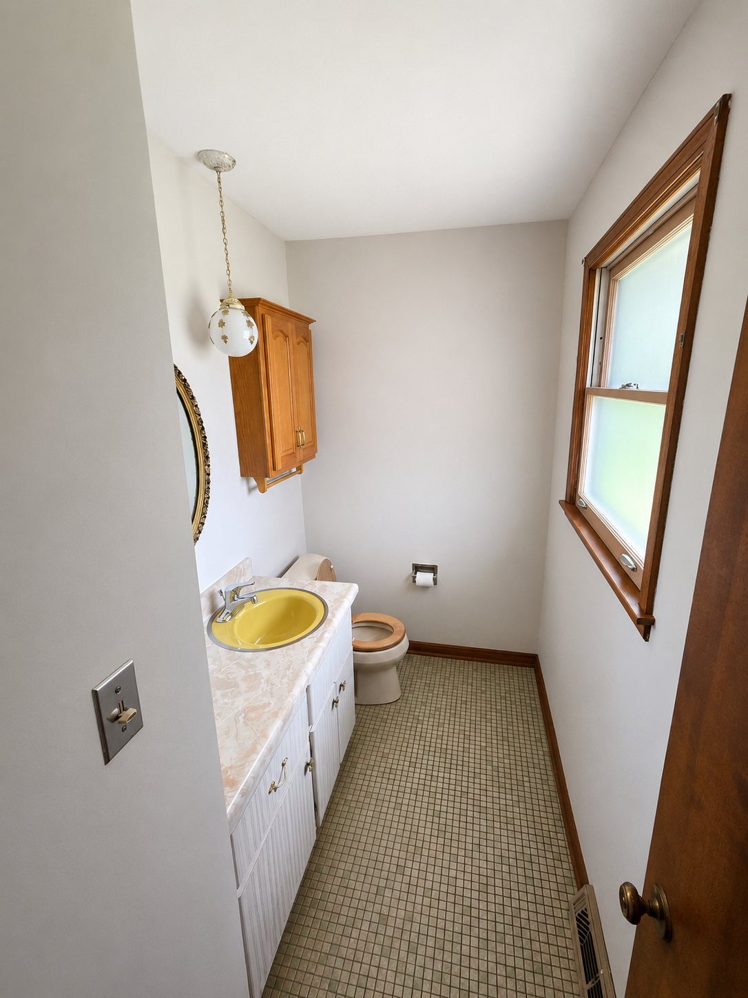 Before: cramped primary bathroom with a yellow drop-in sink, laminate vanity, oak wall cabinet, and dated mosaic tile floor