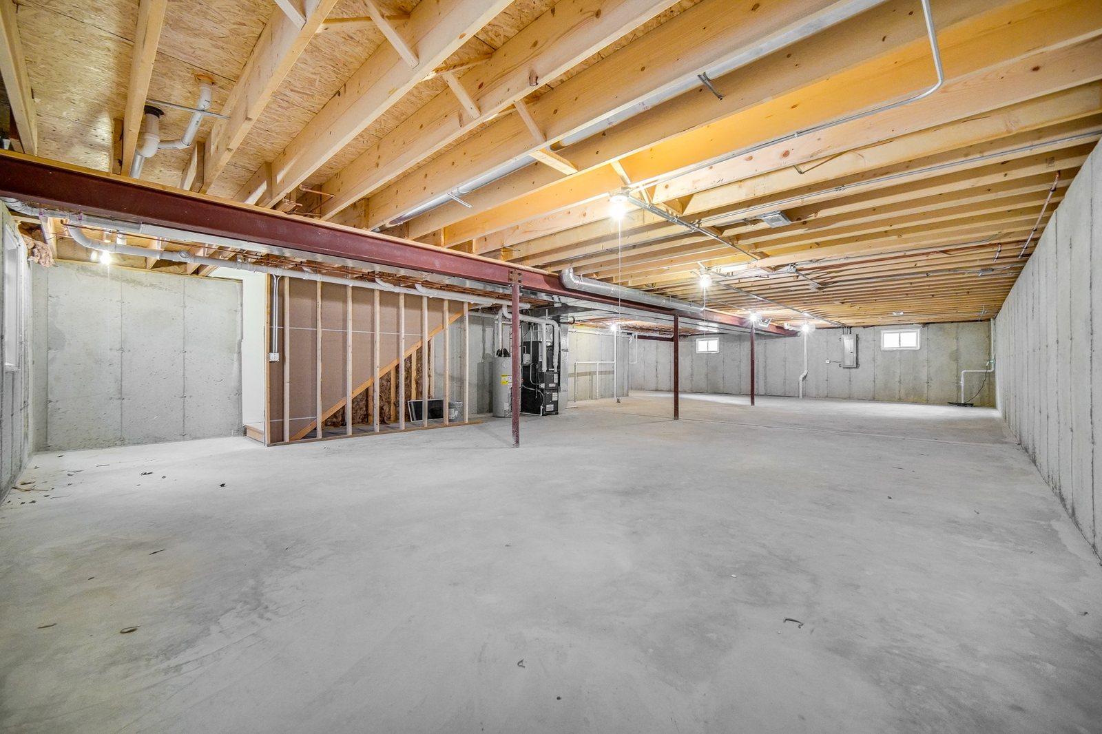 Full unfinished basement with poured concrete walls, steel beam, and plumbing roughed in for future finishing