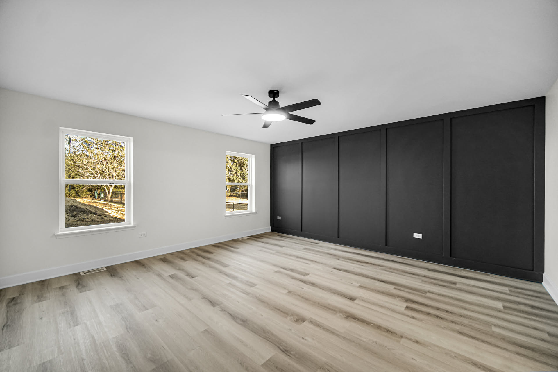 Bedroom with a black grid-panel accent wall, ceiling fan, and vinyl plank flooring