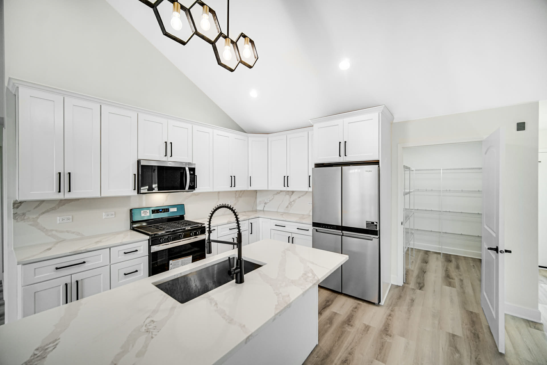 New construction kitchen with white shaker cabinets, quartz island, and full-height marble-look backsplash