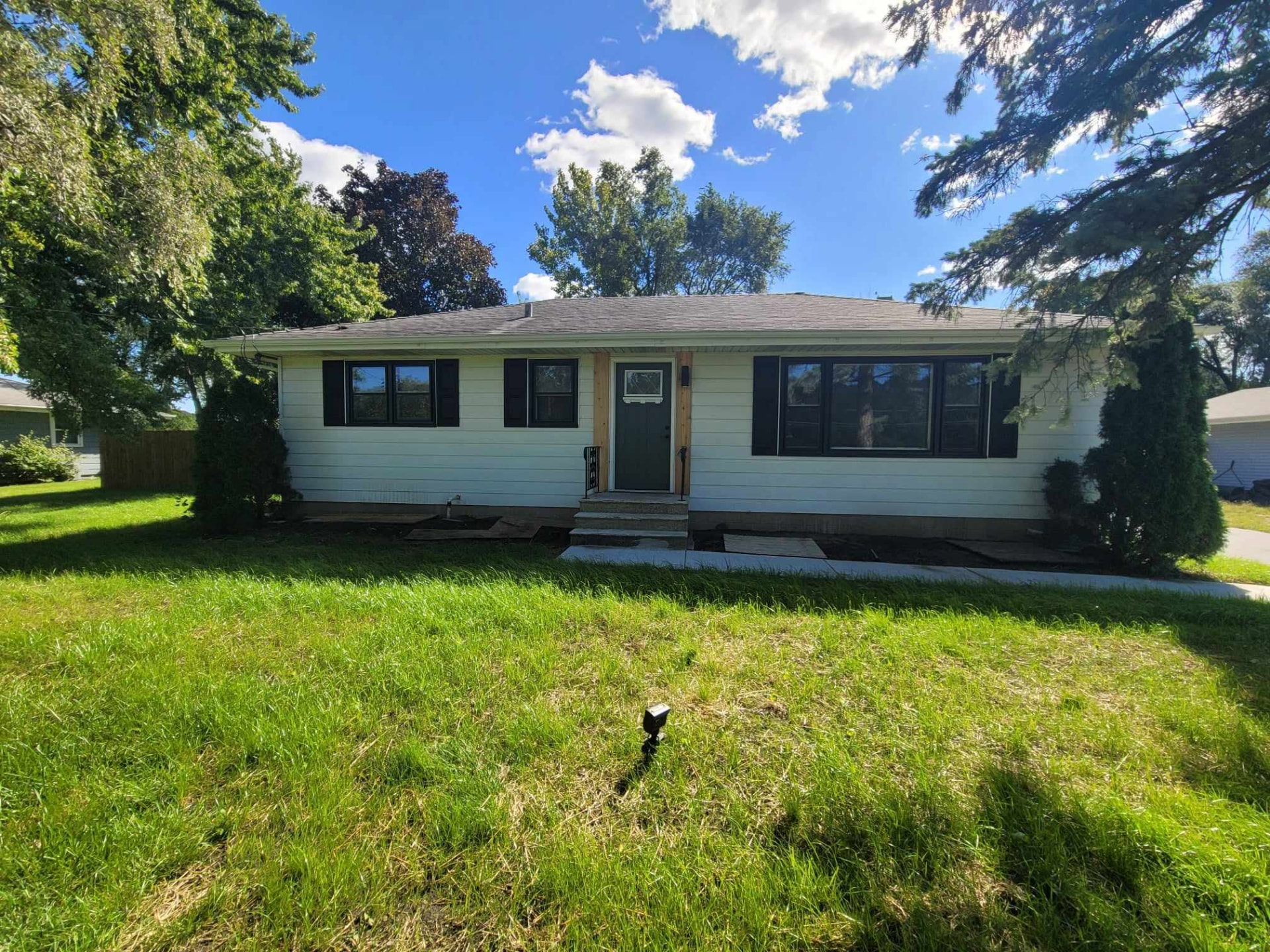 After: cleared landscaping, fresh siding, black shutters, and a new front entry on the Mokena ranch
