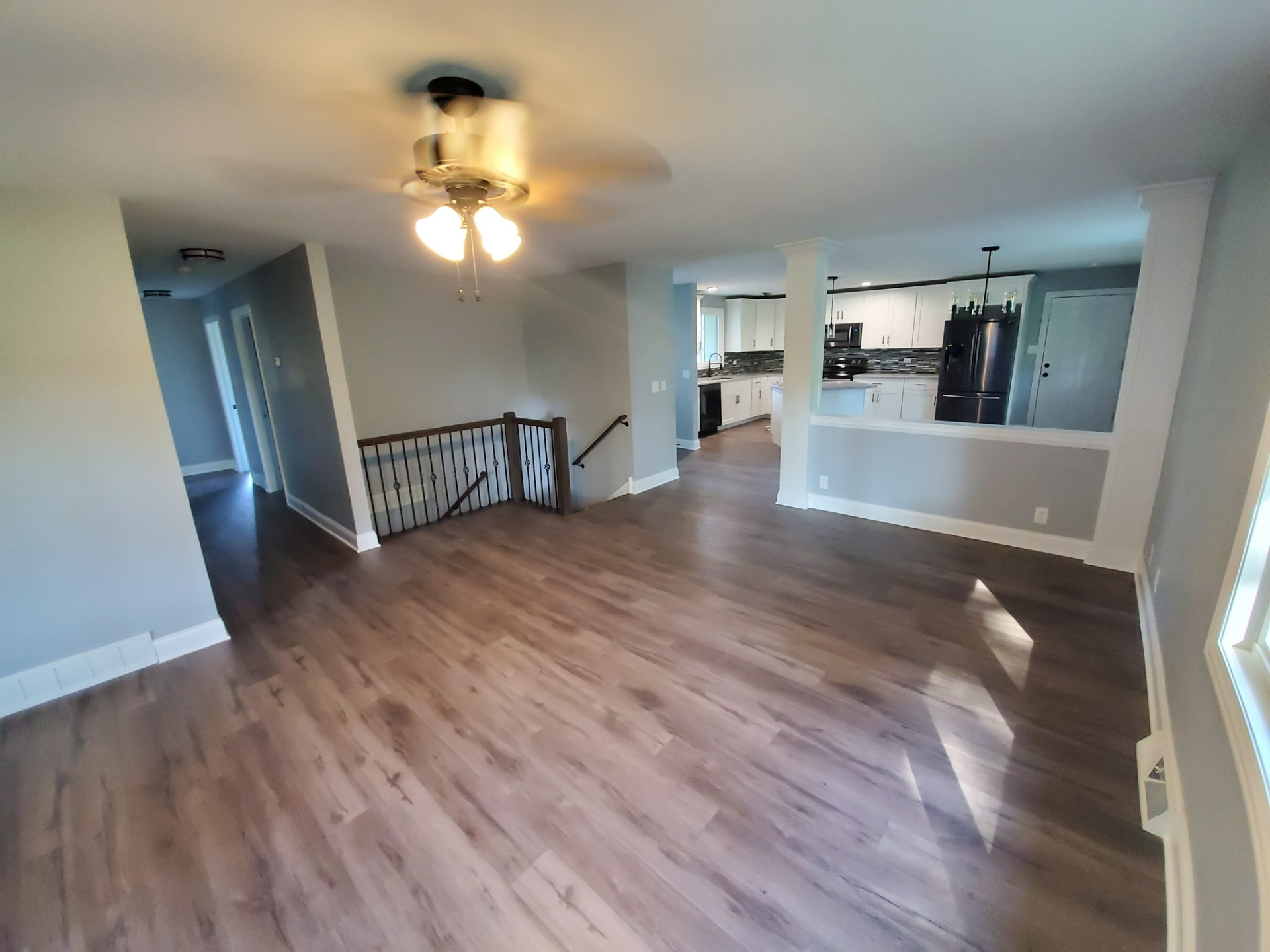 Open-concept living and dining area created by relocating the staircase, with vinyl plank floors and a new iron stair railing