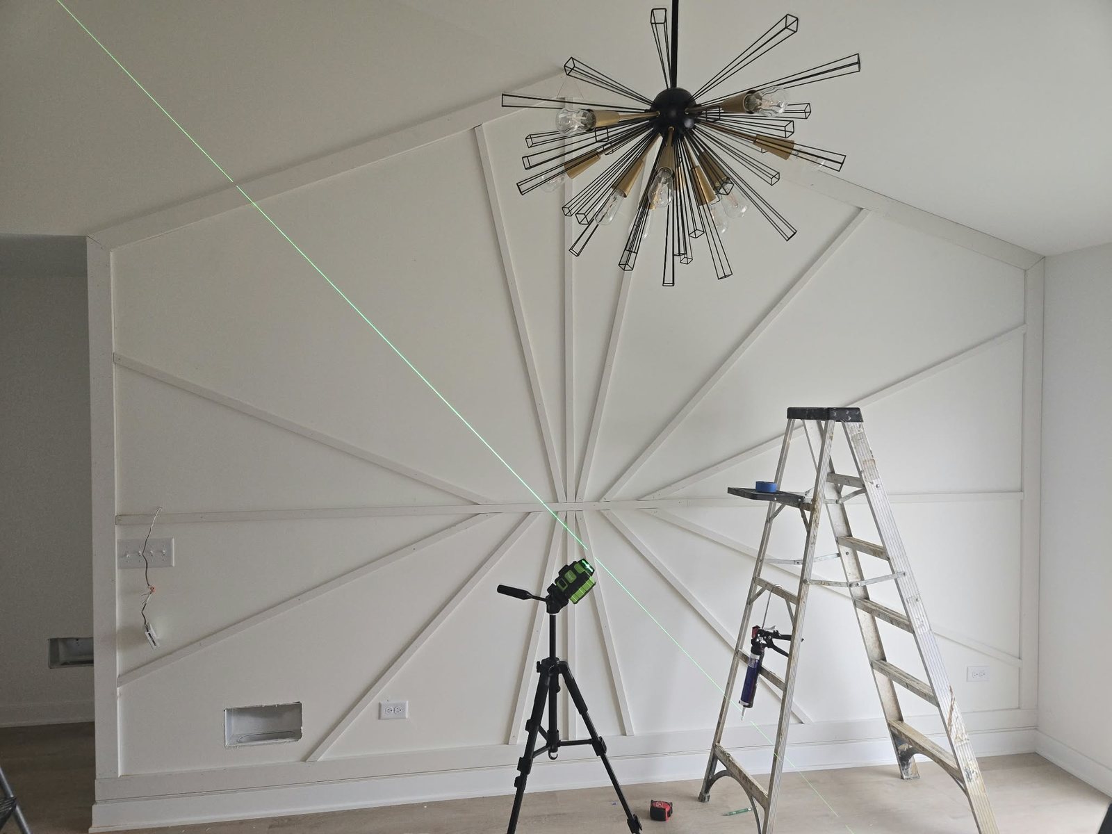 Sunburst accent wall trim being laid out with a laser level in a vaulted dining area
