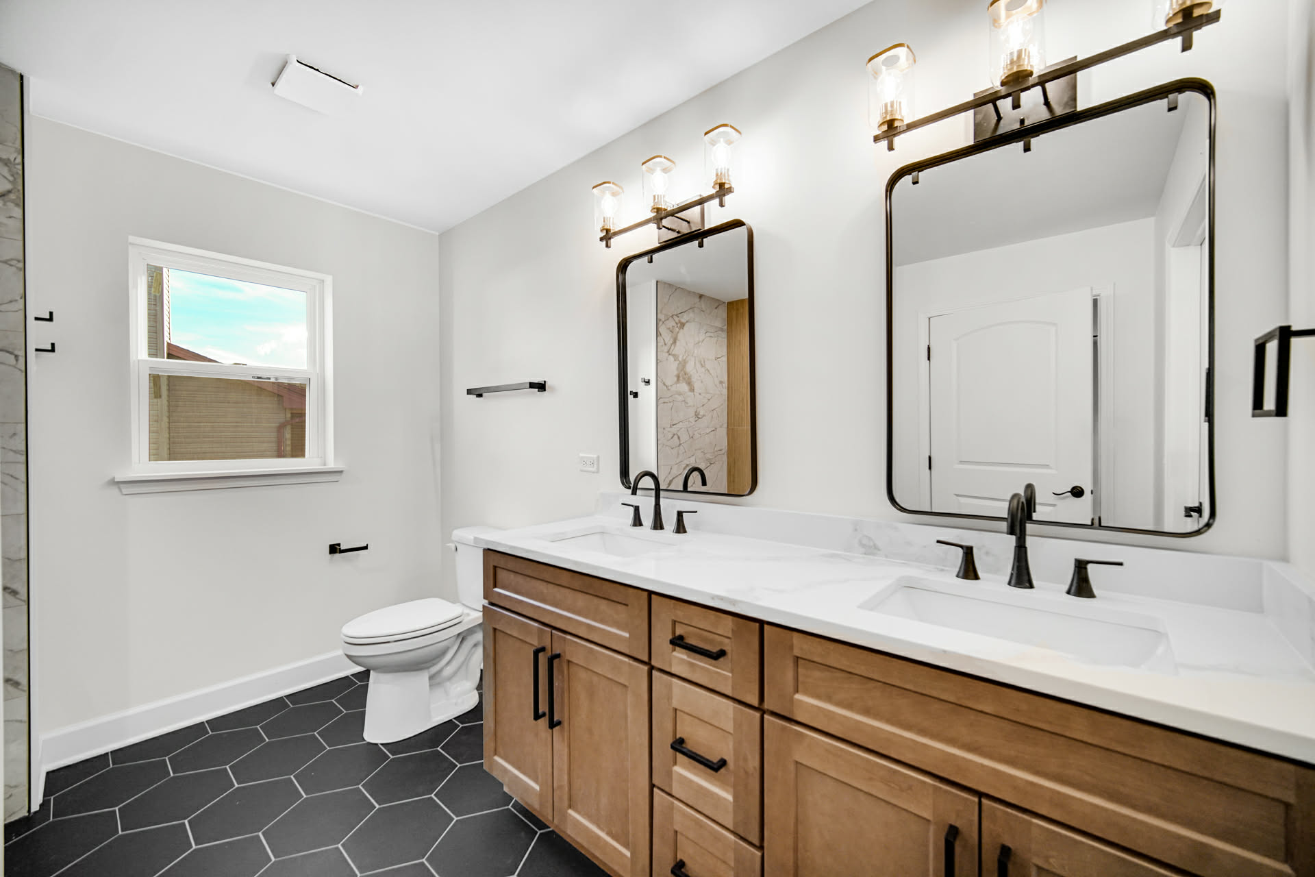 Primary bathroom with double stained-maple vanity, quartz top, and black hex tile floor