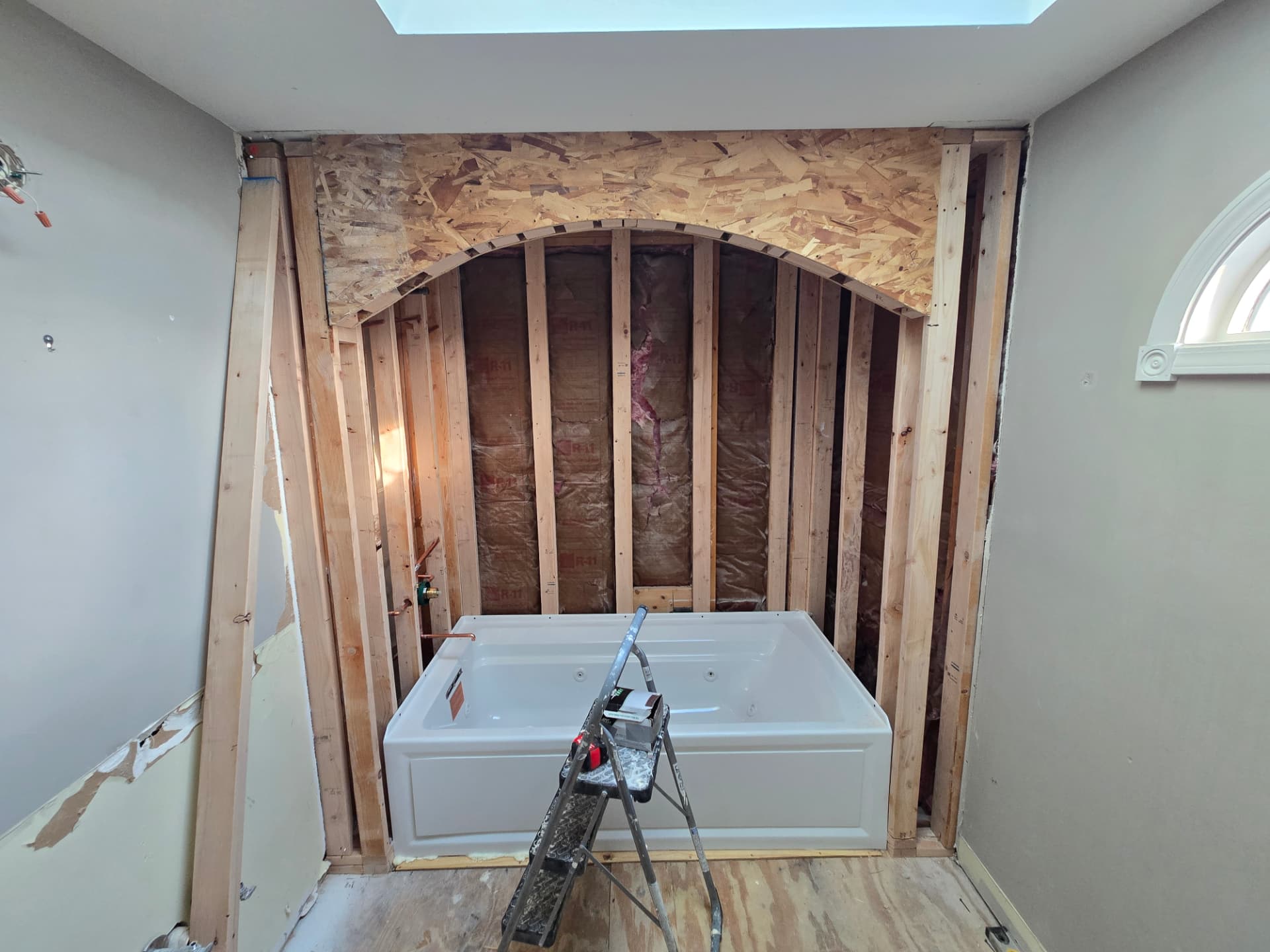 Bathroom opened to framing during Lockport Illinois remodel with new white jetted tub set in place and rough plumbing visible