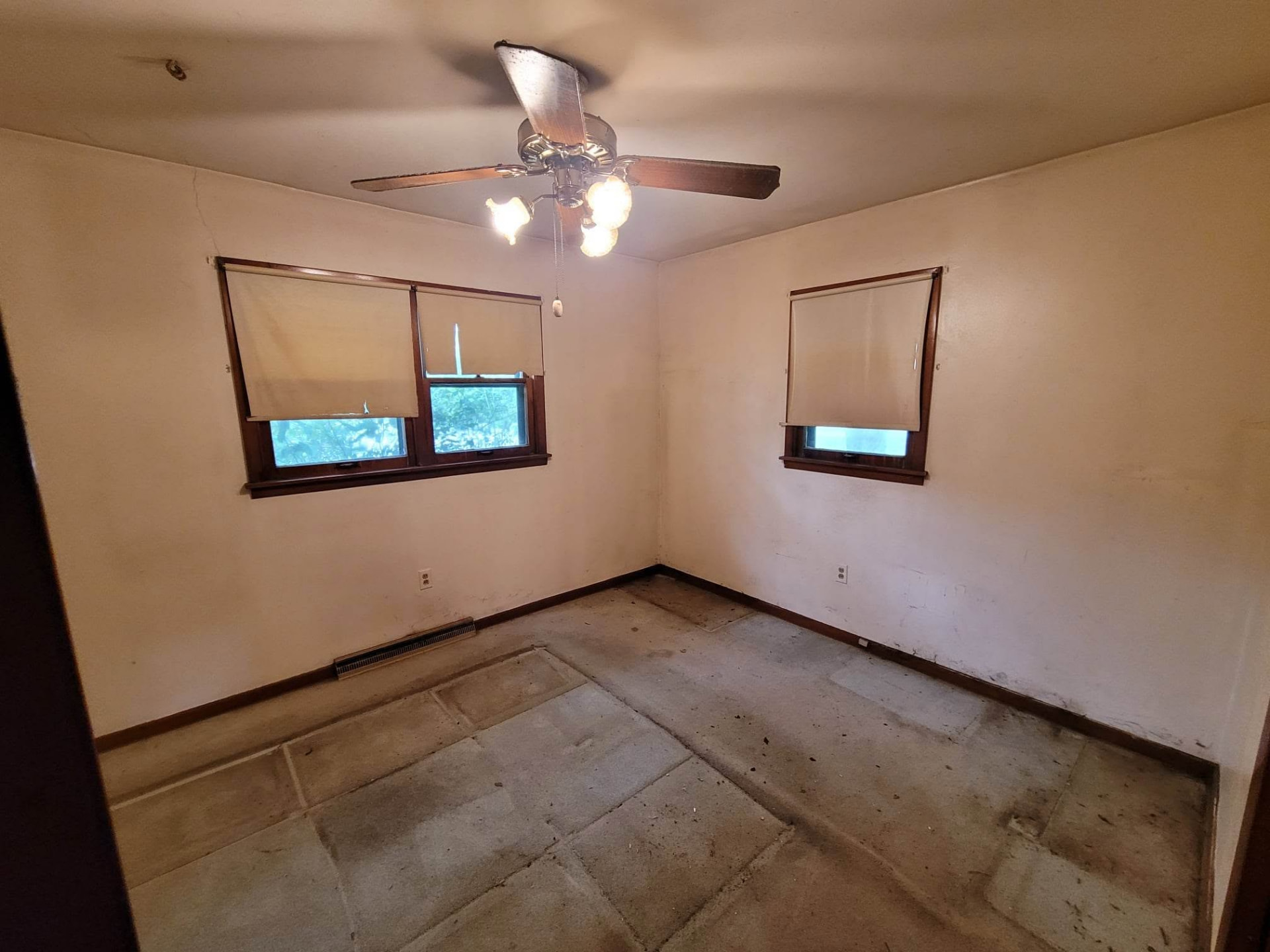 Before: bare bedroom with stained walls, old shades, and no flooring