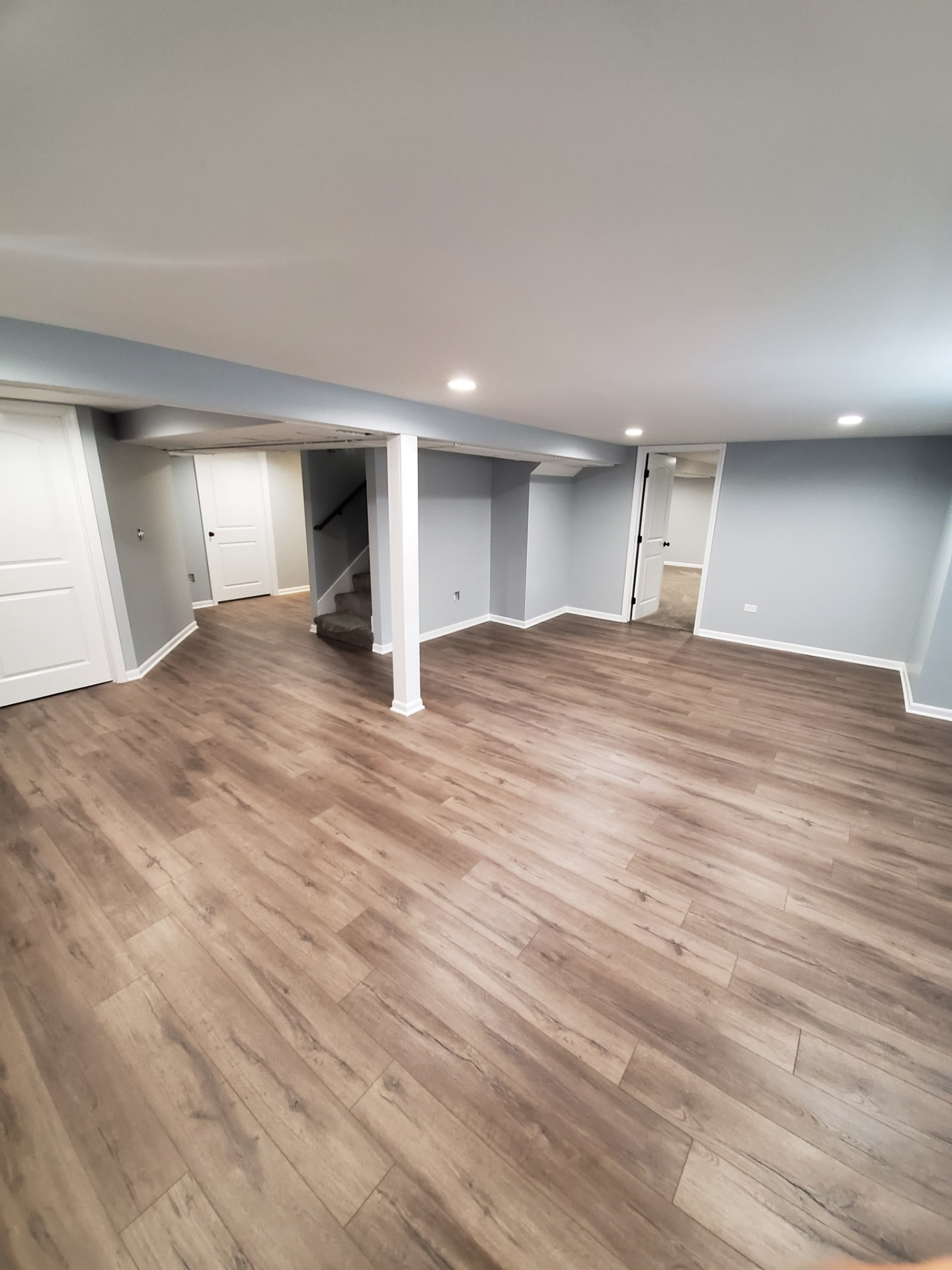 Fully finished basement with a new full bathroom, recessed lighting, gray walls, and wide plank flooring