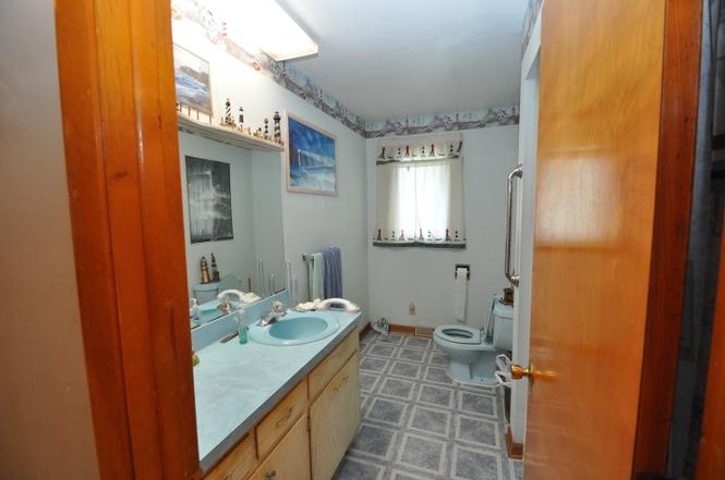 Before: dated bathroom with blue sinks, laminate vanity top, and patterned vinyl floor
