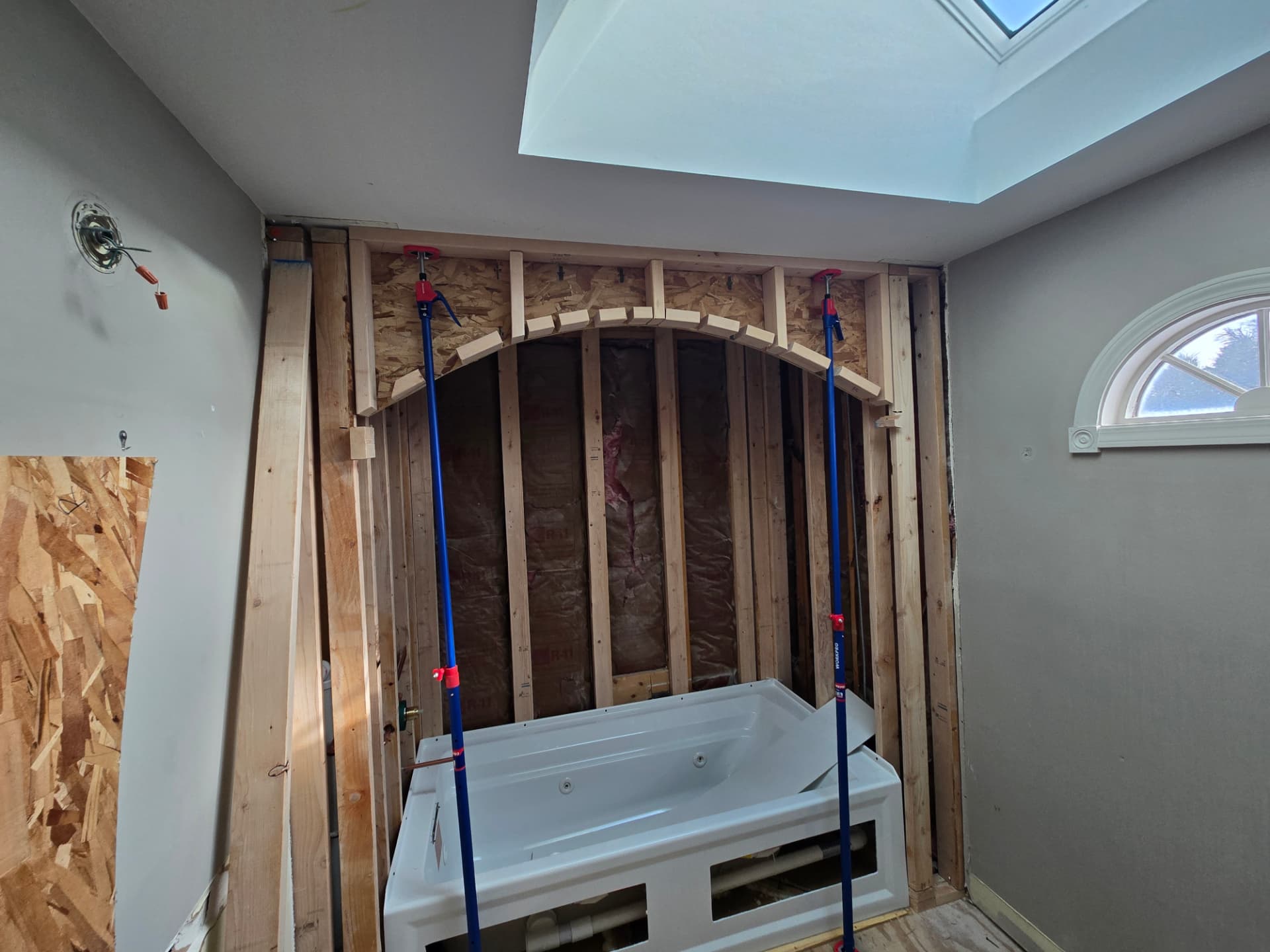 Custom arched bathtub alcove framing installed during Lockport bathroom remodel with support poles holding the curved header in place above the tub