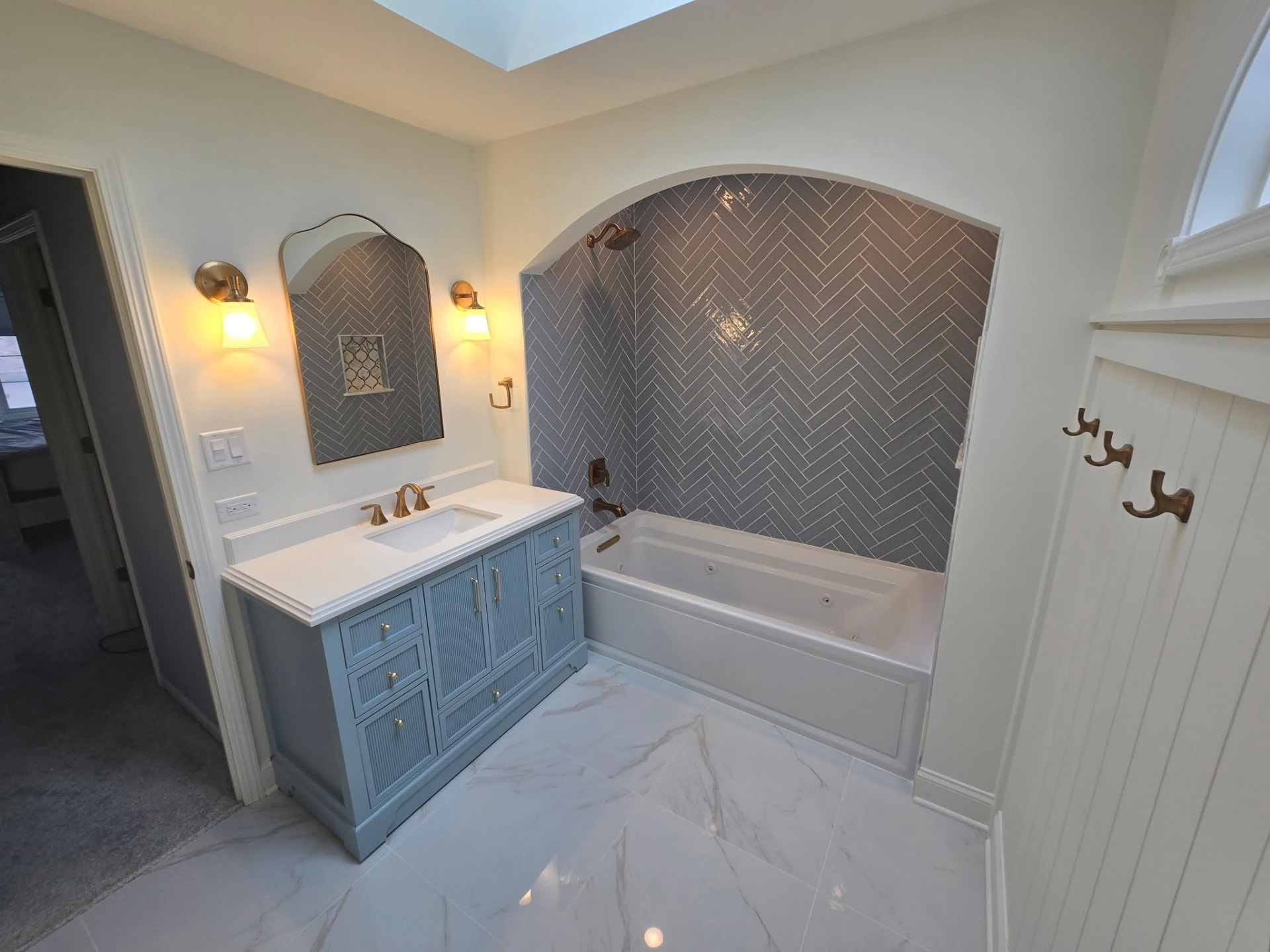 Lockport bathroom remodel with skylight, arched mirror, and soaking tub under herringbone tile