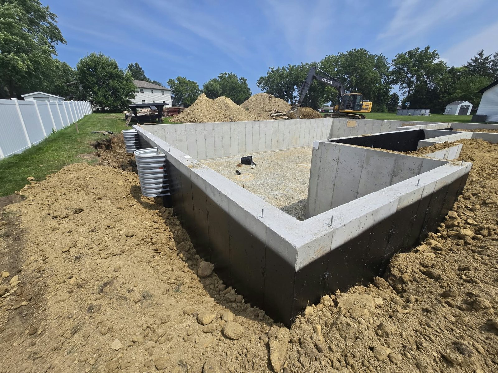 Poured concrete basement walls with exterior damp-proofing and window wells at a new construction home in Manteno, Illinois