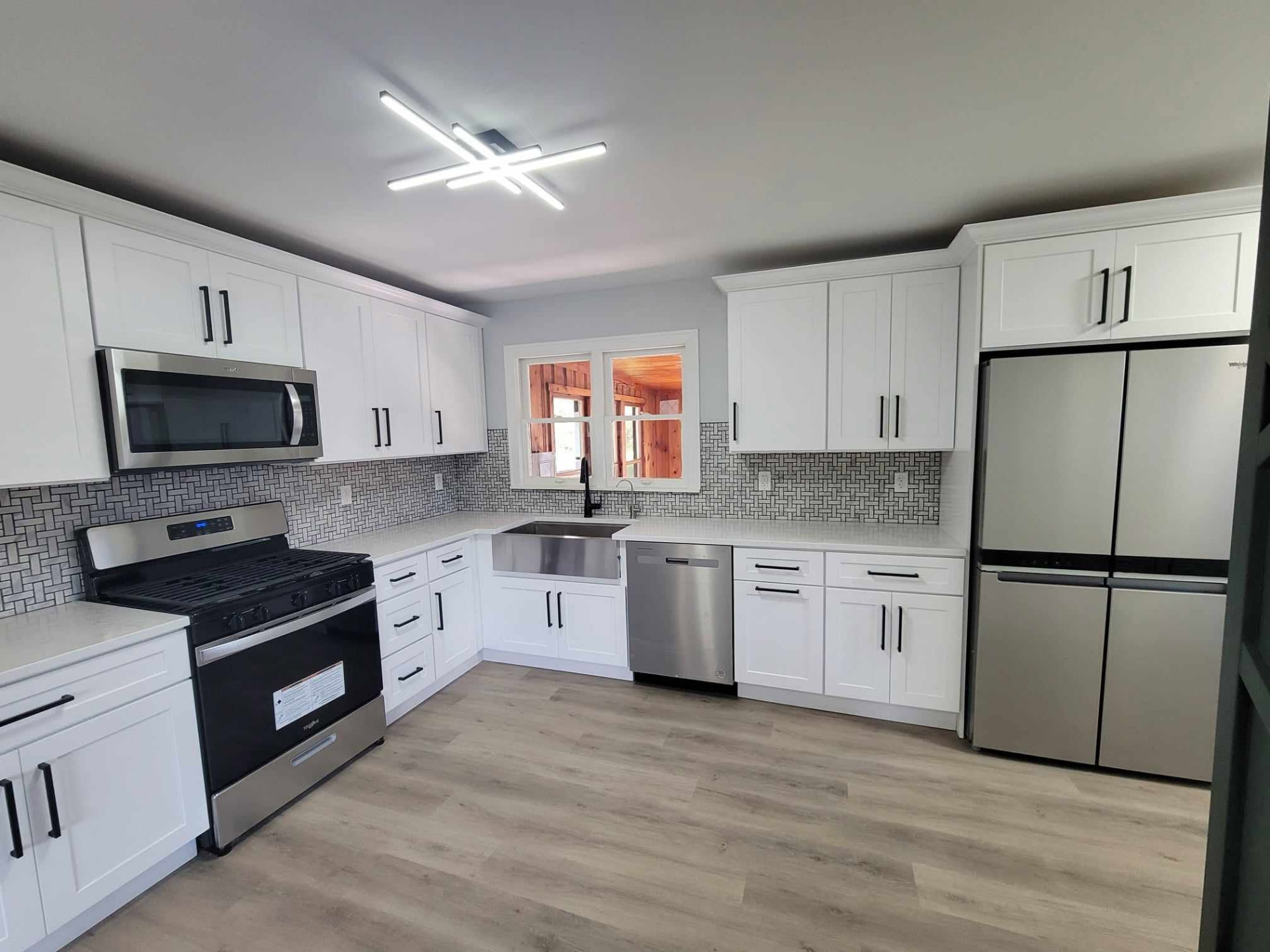 After: white shaker cabinets, quartz counters, basketweave tile backsplash, and stainless appliances