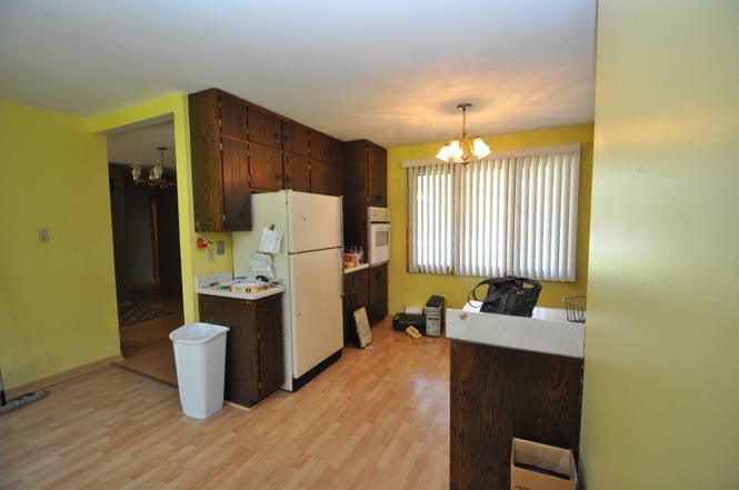 Before: cramped kitchen with dark wood cabinets, yellow walls, and laminate flooring